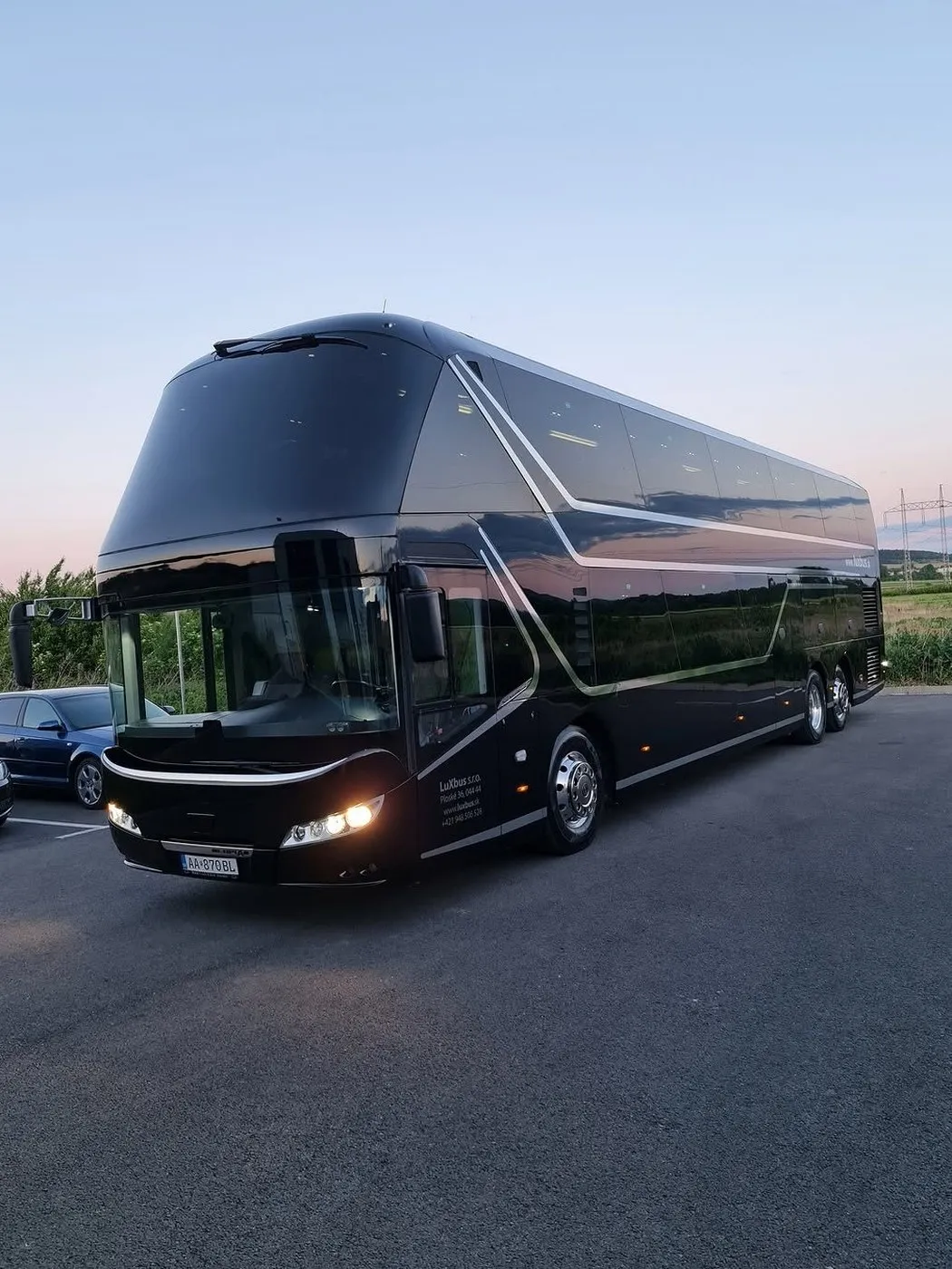 Čierny poschodový autobus Neoplan Skyliner s lesklým lakom pri západe slnka